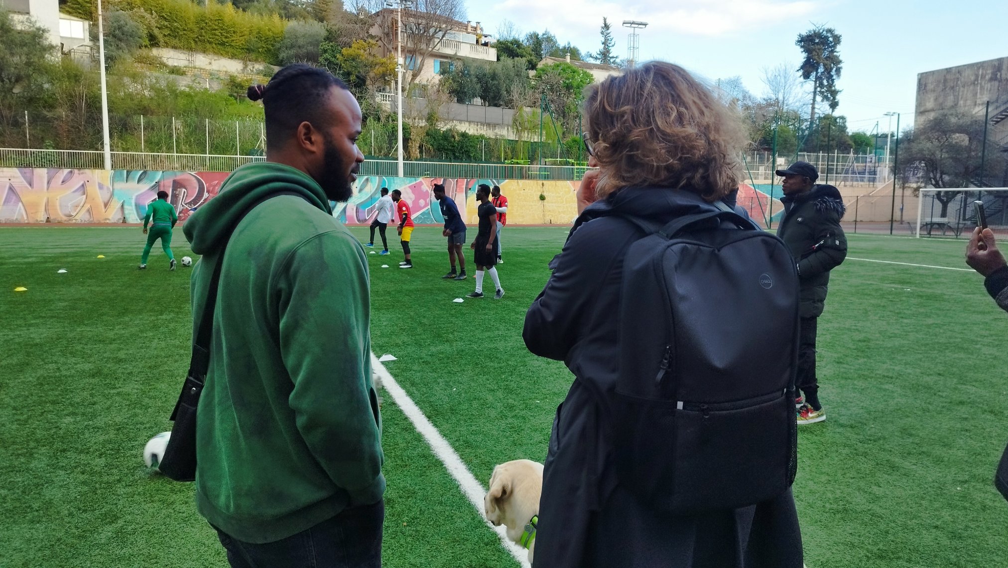 Deux personnes en discussion devant des joueurs qui s'entrainent