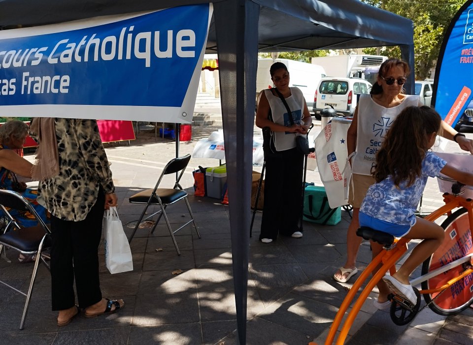 Accueil estival du Secours Catholique à Vallauris avec le vélo smoothie Personnes en extérieurs sur un stand et enfant qui pédale
